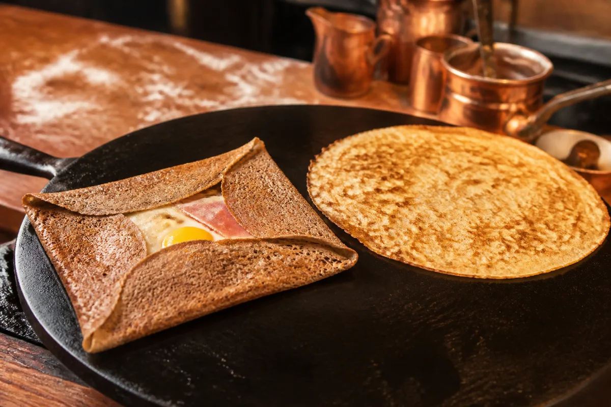 Galette de blé noir pliée en carré à côté d&rsquo;une crêpe de froment